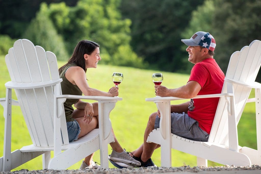 a couple enjoying wine outdoors in large Adirondack chairs